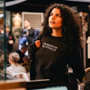 A stunning image of a beautiful woman wearing the Humans of Australia Black Jumper, showcasing its elegant fit and versatile style.