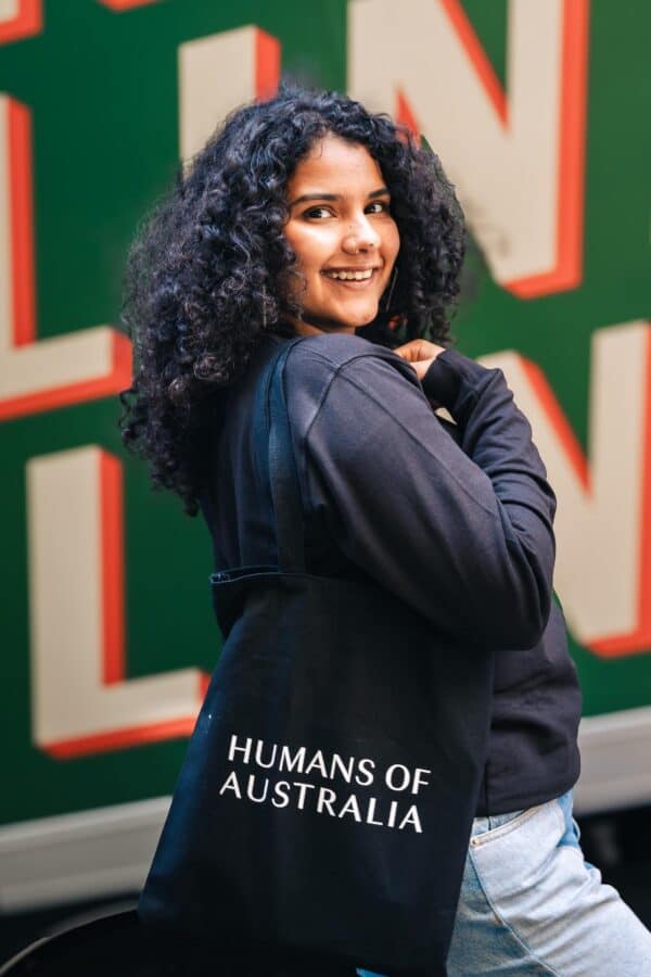 A fashionable woman showcasing the Humans of Australia Tote Bag, perfect for both style and functionality