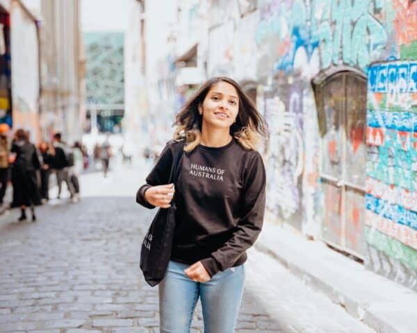 A chic image of a woman wearing the Humans of Australia Black Jumper, perfect for all occasions.