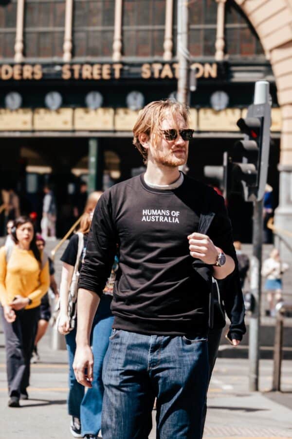 A man with glasses perfectly styling the Humans of Australia Black Jumper for a sleek look