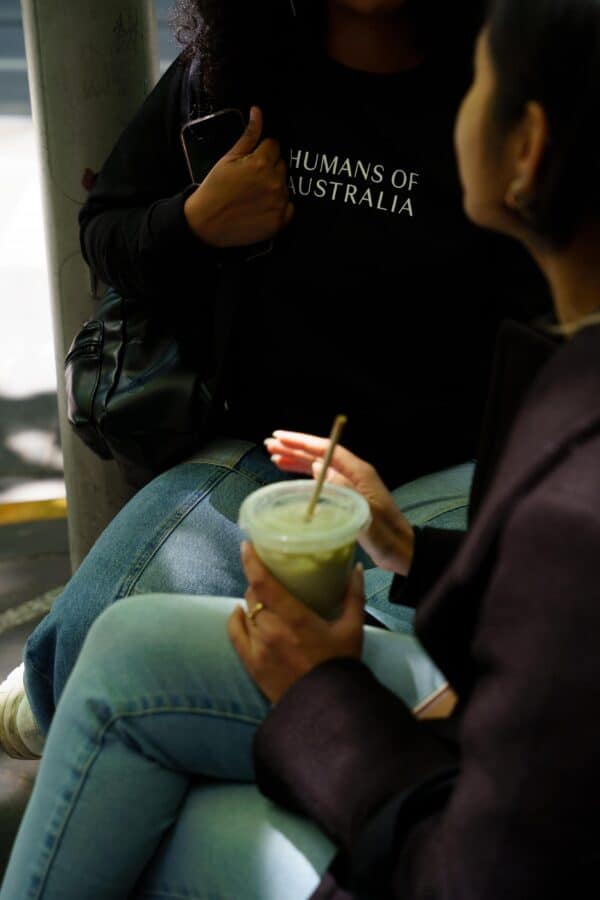 Two friends enjoying their day while flaunting the comfortable Humans of Australia Black Jumpers.